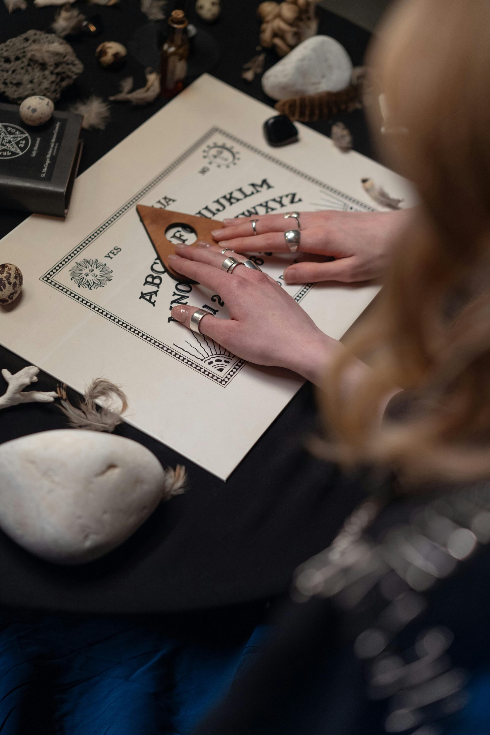 Hands using a planchette on a spirit board.